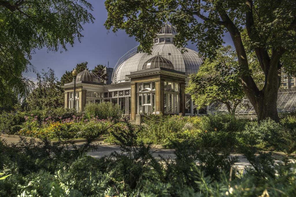 Allan Garden's green house. glass dome roof. blue sky, sunny. green plants growing in the foreground