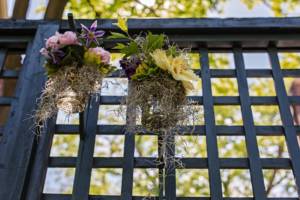 Two hanging floral arrangements with wood latices in the background
