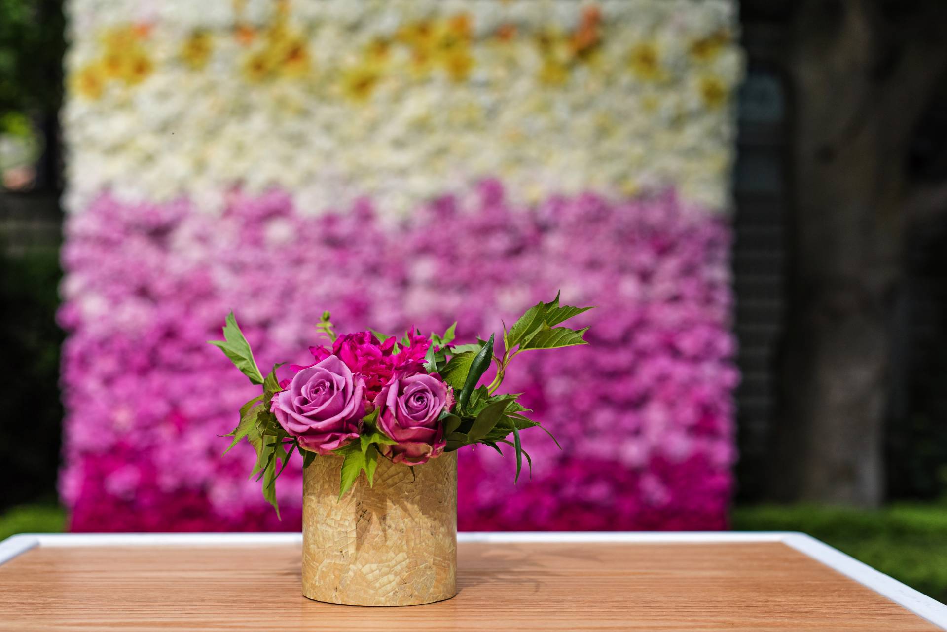 floral arrangement set on cruiser table with a multi-coloured flower wall faded in the background