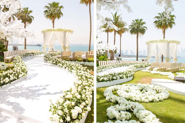 Ceremony aisles with beautiful white florals and palm trees on the beach.