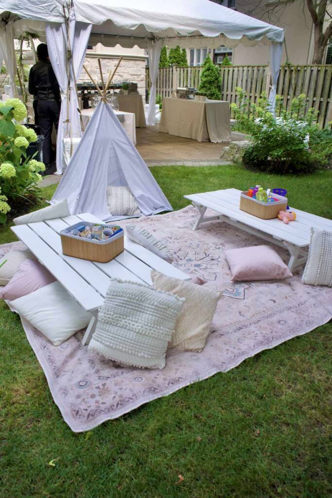 Children Play area packed with pillows and children toys for backyard wedding. blanked on grass with a small tent