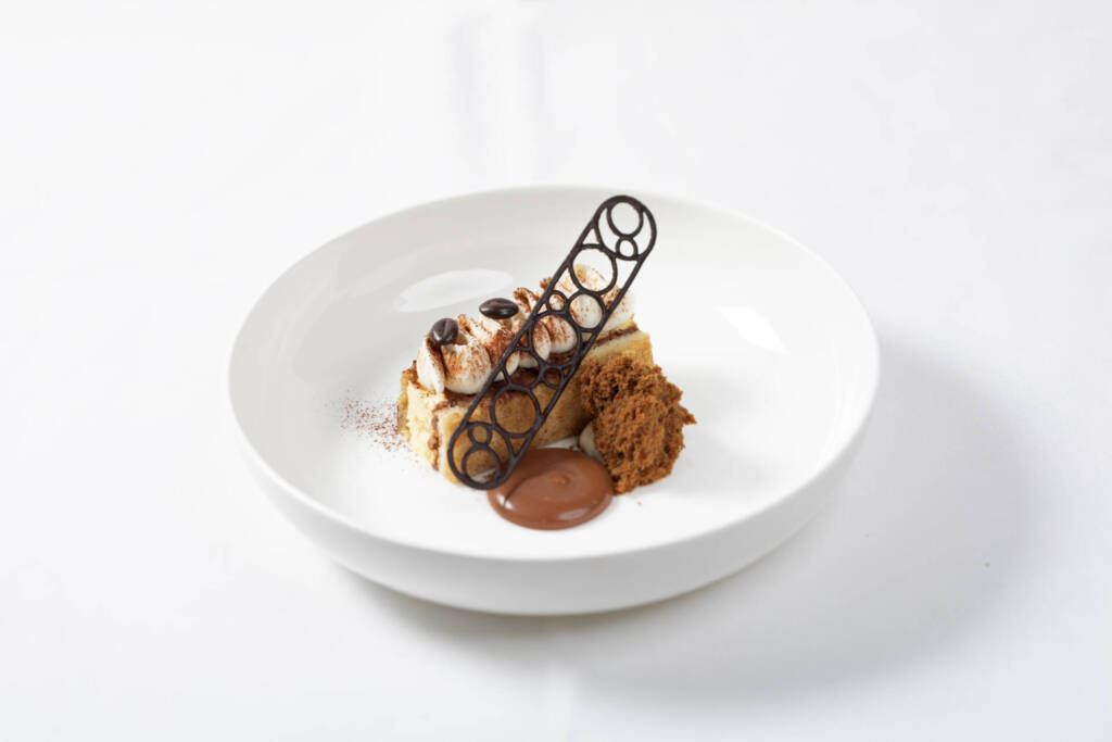 Plated Tiramisu dessert with expresso dust, chocolate and coffee bean garnish